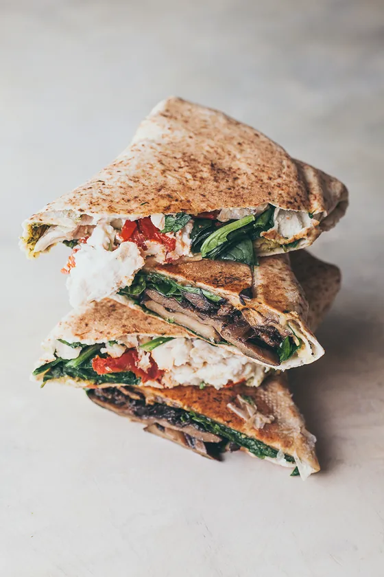 Toasted sandwiches stacked, filled with chicken, spinach and tomato.