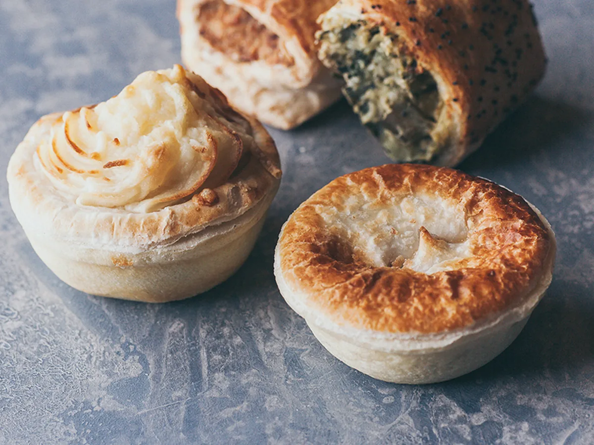 A potato topped pie beside a spinach and cheese roll.