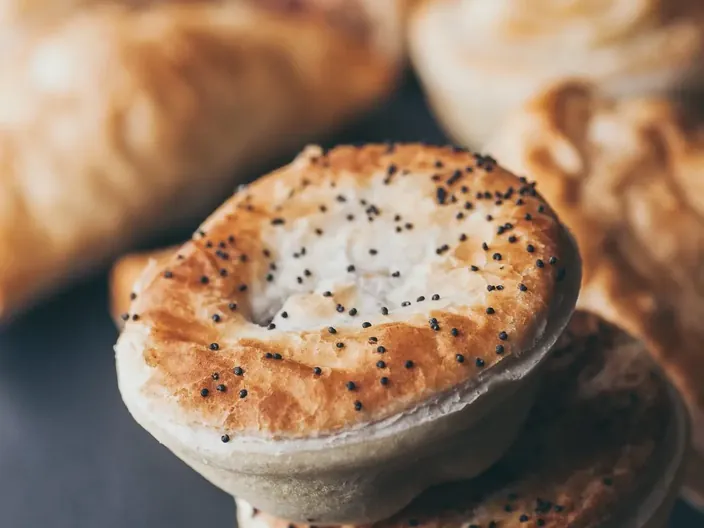 A stack of poppy seed topped pies.